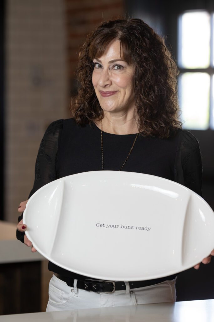 photo of a woman holding a plate that reads: get your buns ready | Gina Forcatto