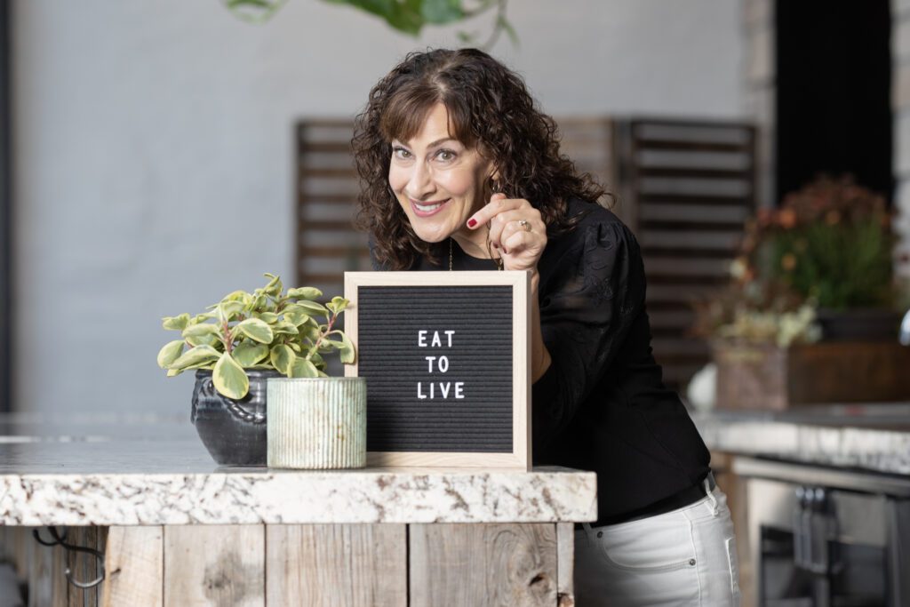 photo of Gina Forcatto with a sign: eat to live